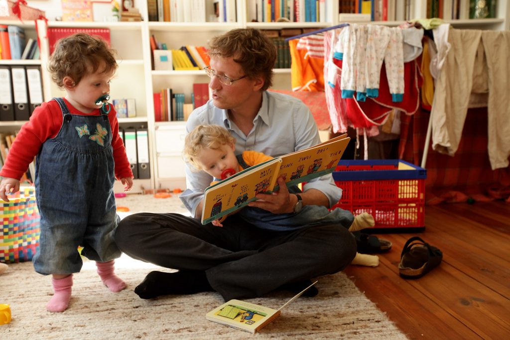 BERLIN - AUGUST 31: Oliver H., 42, a married federal employee on 6-month paternity leave, reads to his twin 14-month-old daughters Alma (R) and Lotte at his home on August 31, 2010 in Berlin, Germany. Under German law married couples may take 14 months parent leave, to be divided between the two spouses, during which an individual receives two thirds of his or her normal income from the state, up to EUR 1,800 a month. In order to encourage more fathers to take paternity leave, German Family Minister Kristina Schroeder is seeking to lengthen parent leave from the current 14 months to 16 months, though German Finance Minister Wolfgang Schaeuble sees the measure as too expensive. 