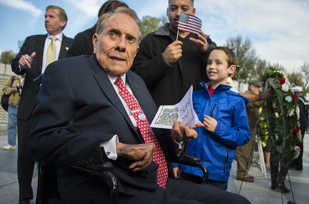 Former US Senator and World War II veteran Bob Dole (C) holds a card given to him by a young boy (R) after laying a wreath at the World War II Memorial on Veteran's Day in Washington, DC, November 11, 2015. 