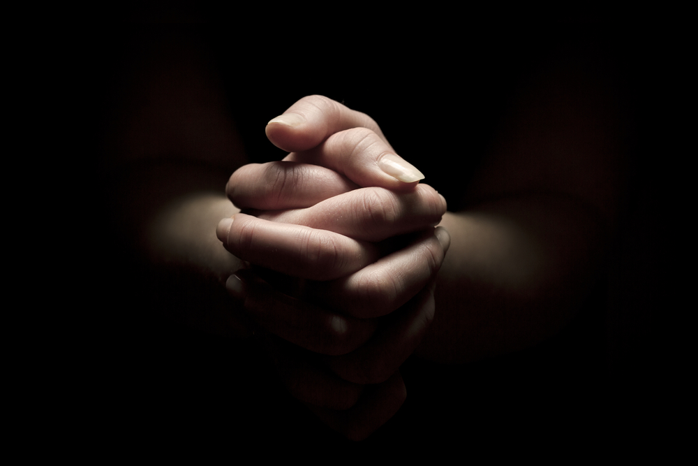 Woman praying with hands folded to God.